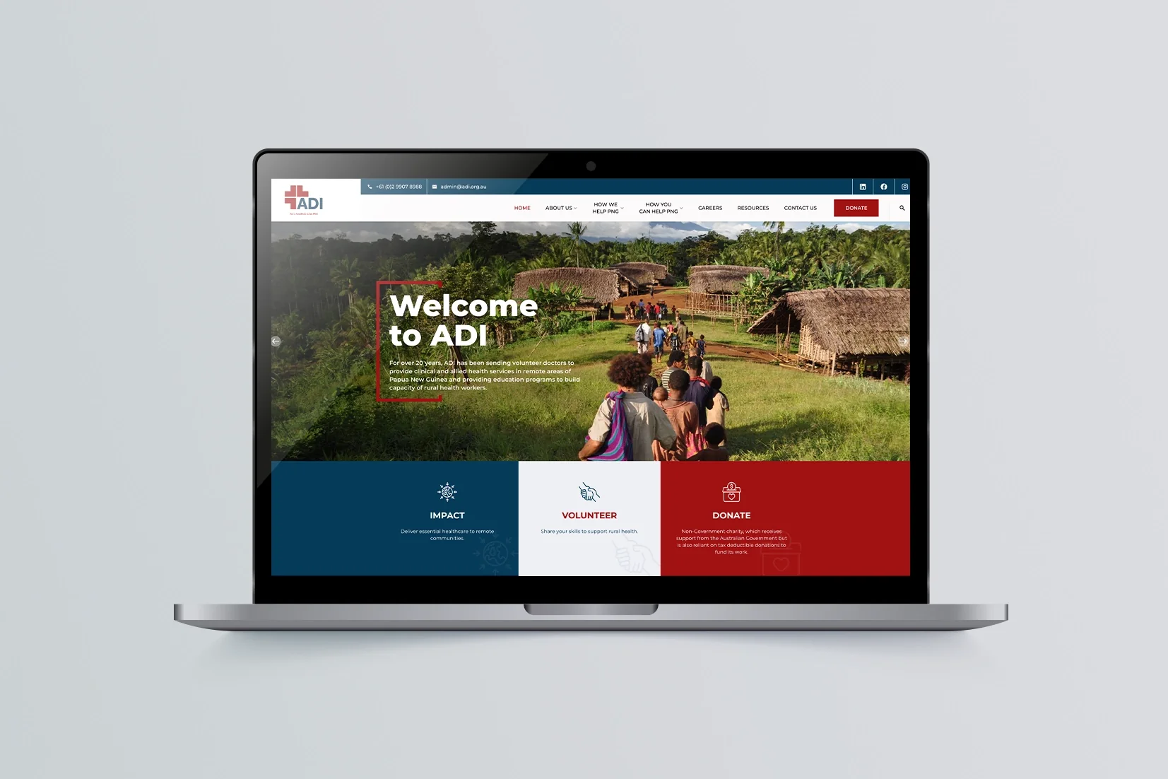 A realistic mock-up of a generic laptop displaying the "Welcome to ADI" website homepage. The screen features a hero image of people walking through a lush rural village and navigation options for Impact, Volunteer, and Donate.